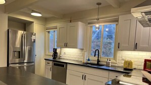 A modern kitchen with stainless steel appliances, white cabinetry, and a large island.