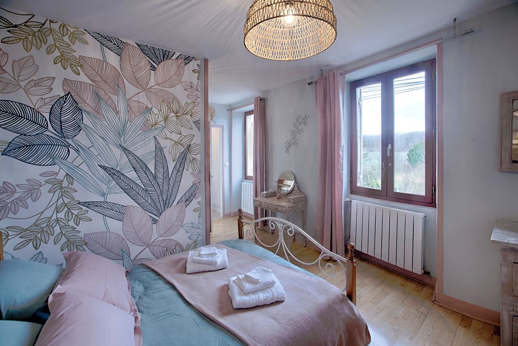 A bedroom with a bed, a dresser, a mirror, and a window with curtains.