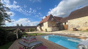 Eine Holzterrasse mit Liegestühlen und einem Swimmingpool.