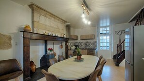 Eine geräumige Küche mit einer großen Kochinsel, Holzhockern und einem modernen Kühlschrank.