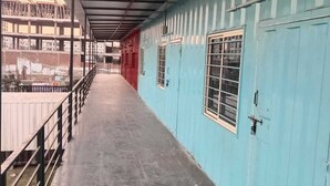 A corridor with a metal roof and blue walls, leading to a red door. - Vrinda Resort by Dcrest  (Mathura)