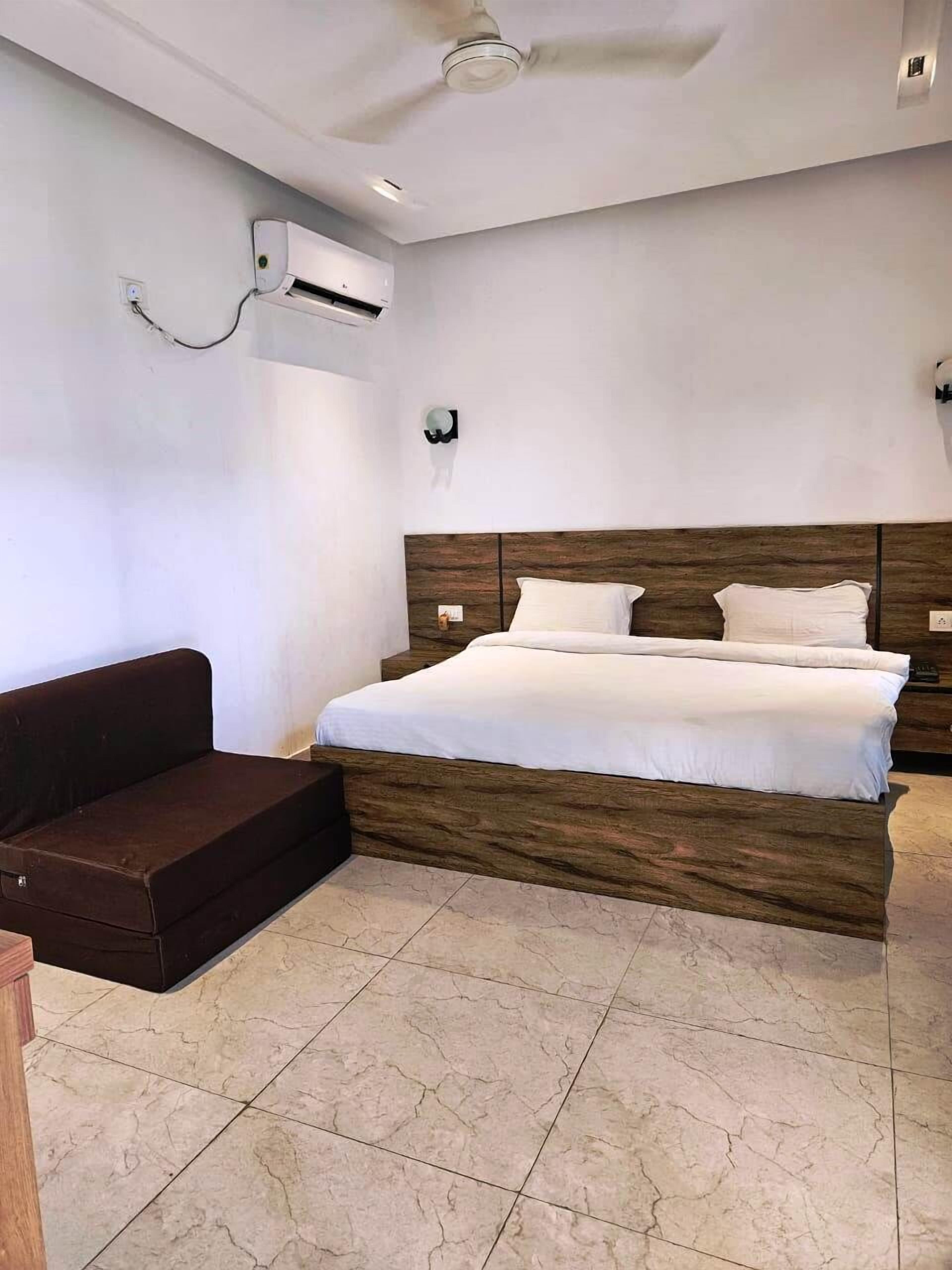 A bedroom with a bed, a dark brown sofa, and a ceiling fan.