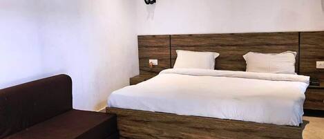 A bedroom with a bed, a dark brown sofa, and a ceiling fan.