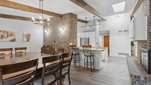 Una cocina amplia con pared de ladrillo decorativa, vigas de madera e iluminación moderna.
