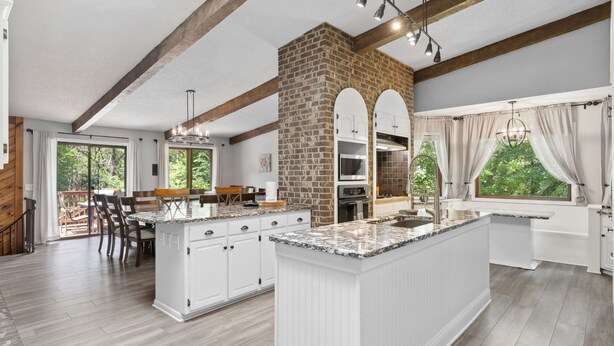 Una cocina amplia con una isla grande, armarios blancos y una pared de ladrillo decorativa.