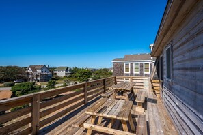 A wooden deck with picnic tables overlooking a residential area.