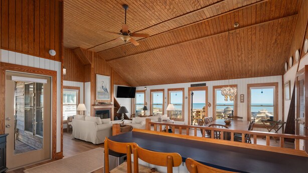 A spacious room with a wooden ceiling, a large dining table, and a view of the ocean. - D124- Classic Duck Oceanfront - 4 Brs Outstanding Ocean Views & Comm. Pool (Duck)