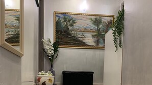 A hallway with a wooden floor, a black bench, a vase with white flowers, and a framed painting on the wall. - Napoleone Luxury Home (Rome)