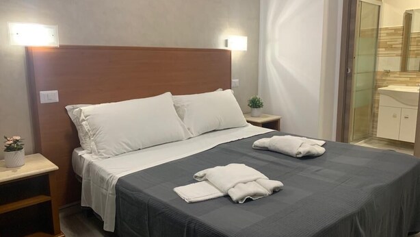 A hotel room with a large bed, two bedside tables, a nightstand, and a small potted plant. - Napoleone Luxury Home (Rome)