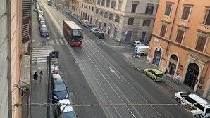 A street view with a bus, cars, and pedestrians. Buildings line the street, some with visible signage. - Napoleone Luxury Home (Rome)