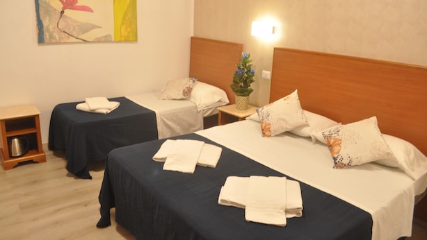 A hotel room with two single beds, a nightstand with a lamp, a small wooden side table, and a wall-mounted artwork. - Napoleone Luxury Home (Rome)