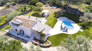 Una casa blanca con techo de tejas, piscina y un porche cubierto.