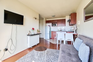 Ett kompakt bostadsutrymme med ett litet kök, en matplats och en sittgrupp med en soffa.