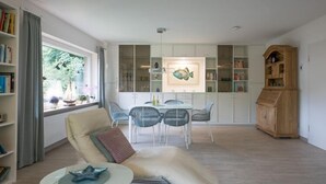 Una sala de estar moderna con un sofá, una mesa de comedor con sillas, una estantería y un aparador.