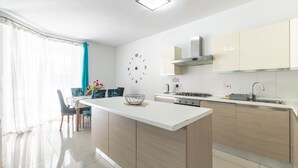 A modern kitchen with a central island, white cabinetry, and a wall clock. - ☆Amazing Apart.w/side Sea View☆8 (San Pawl il-Bahar)