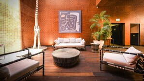 A lounge area with a sofa, two lounge chairs, a round table, and a tall white sculpture. - Luxury Levontin apt near Rothschild (Tel Aviv)