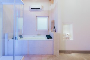 Un baño moderno con cabina de ducha de vidrio, bañera y una ventana pequeña.