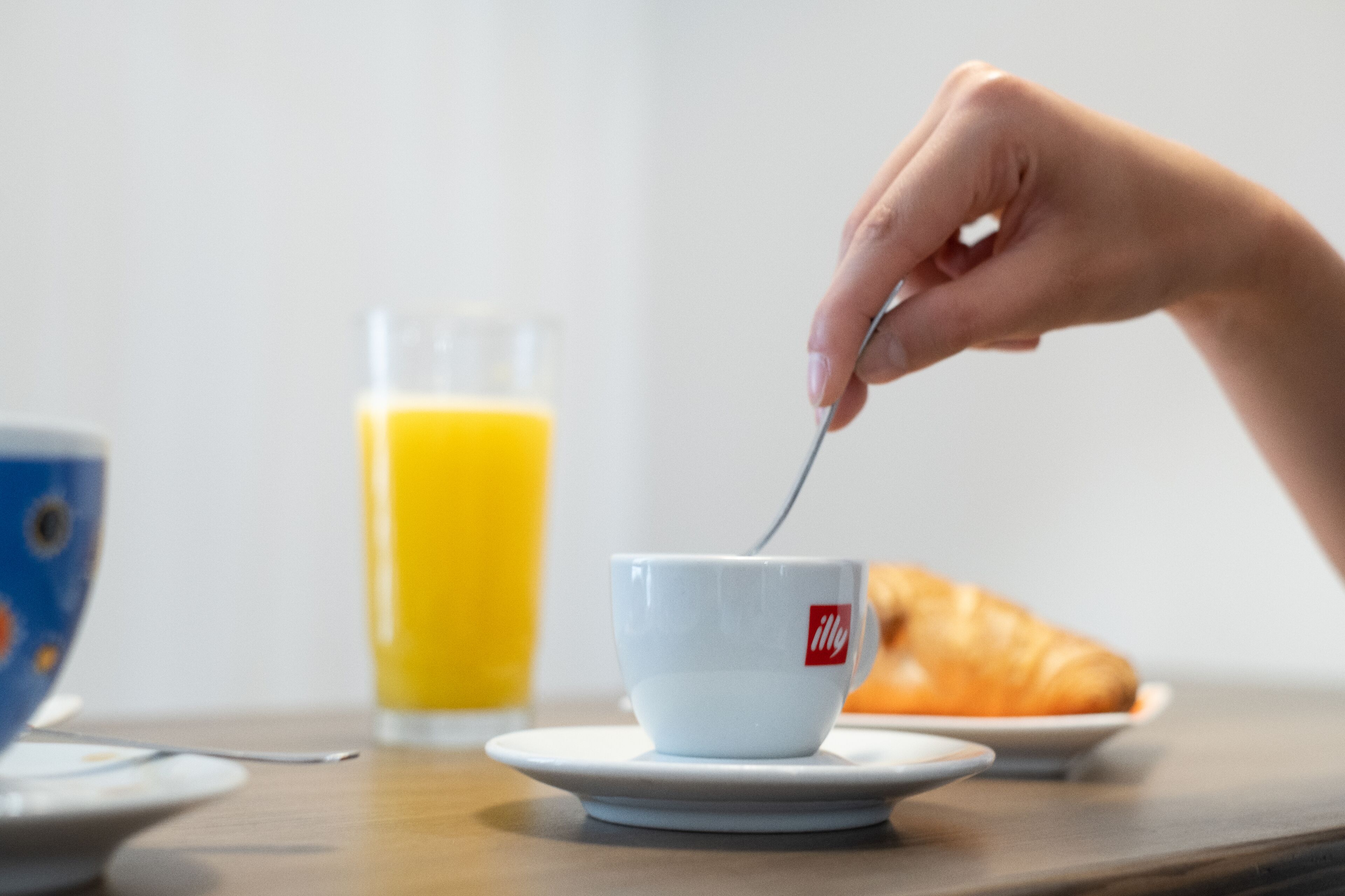 Una mesa con una taza, un vaso de zumo de naranja y un croissant.