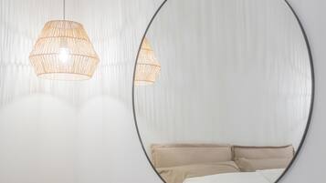 A minimalist bedroom with a bed, bedside table, and a round mirror on the wall.
