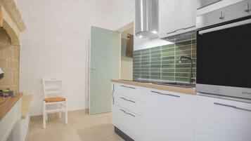 A modern kitchen with white cabinets, a built-in oven, and a green-tiled backsplash.