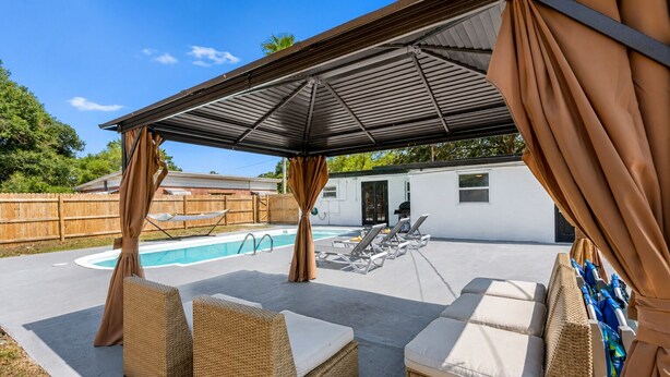 Eine Außenpatio mit Pool, Liegestühlen und einer überdachten Sitzgruppe.