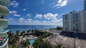 Un hotel con piscina, palmeras y vista al océano.