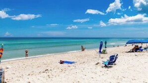 Una playa con agua azul cristalina, una orilla arenosa y algunas sombrillas.