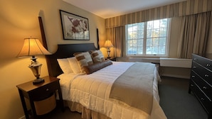 A hotel room with a large bed, two bedside tables with lamps, a dresser, a window with curtains, and a framed picture on the wall. - Ski-In/Ski-Out at Jiminy Peak  in the Country Inn (Hancock)