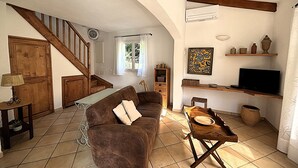 Una sala de estar acogedora con un sofá marrón, una escalera de madera y un televisor sobre una estantería de madera.