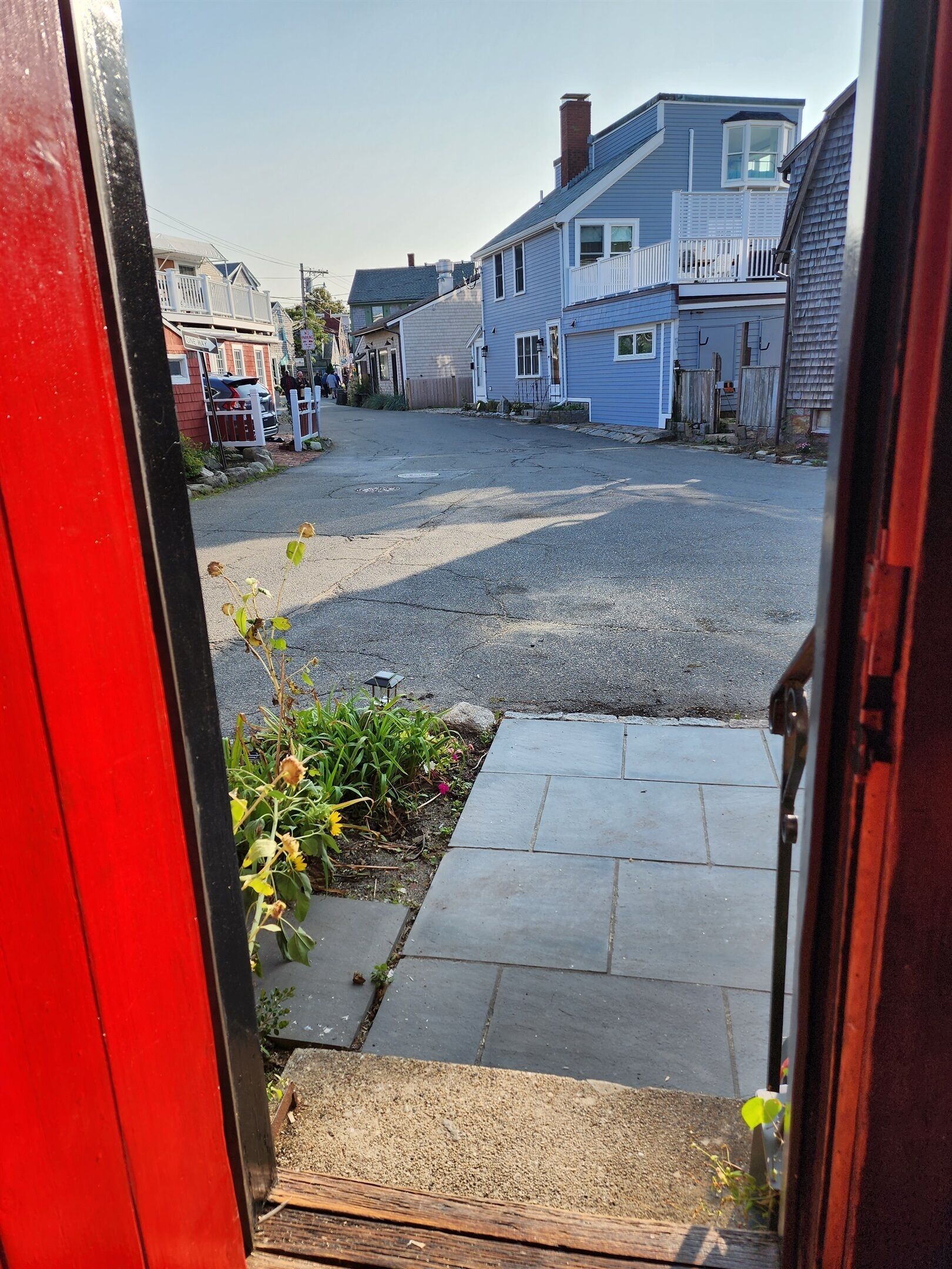 A residential street with houses, a driveway, and a small garden area.