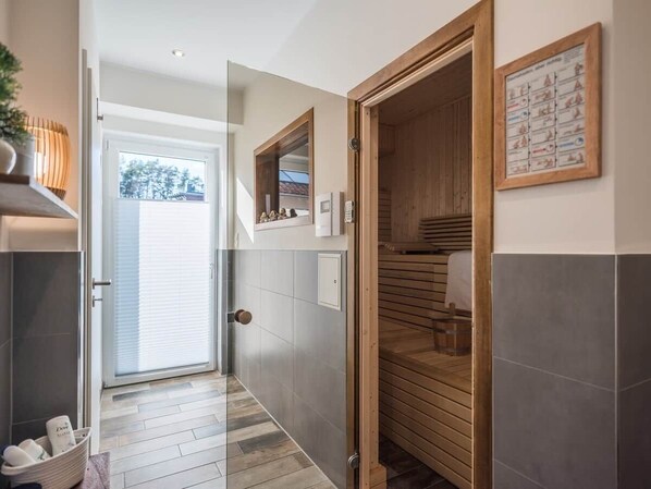 A hallway with a sliding glass door leading to a room, a wooden door, and a tiled floor.
