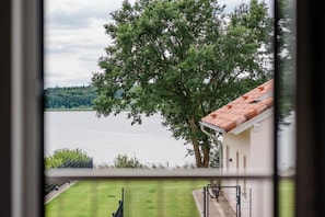 A view of a lake with a tree and a building with a red roof.