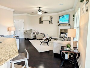 Cozy living space with a fireplace, sofas, armchairs, and a large TV.
