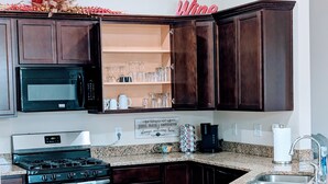 A kitchen with dark wood cabinets, a stainless steel stove, a microwave, and a granite countertop. - Cozy and Modern Home located in a New Secluded Subdivision (Lake Charles)