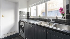 A modern kitchen with a built-in washer, a double sink, and a window with a view of the outside. - Fortified Three Bedroom Home (London)