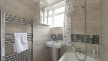 A bathroom with a shower, sink, and towel rack.