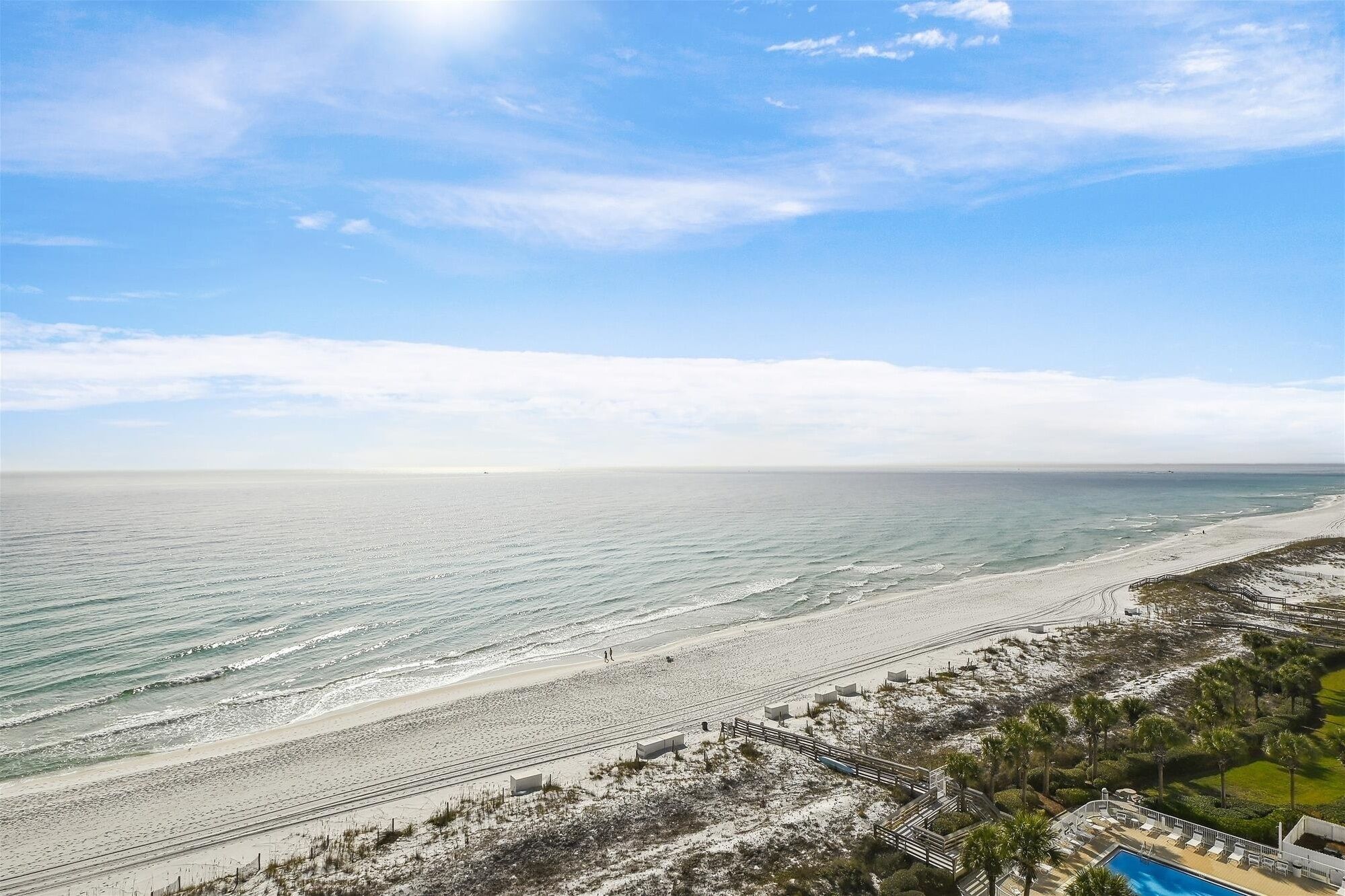 A beach resort with a swimming pool, beach access, and a view of the ocean.
