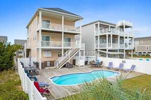 A multi-story building with a pool, outdoor seating, and a staircase leading to the upper levels. - Sea You Soon / 207 Brunswick Ave West 4 Bedroom Home by RedAwning (Supply)