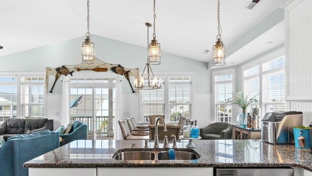 A spacious kitchen with granite countertops, stainless steel appliances, and pendant lighting.