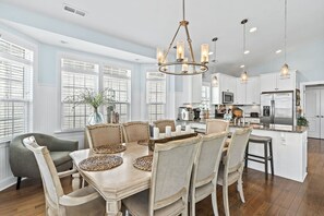 Una cocina amplia con armarios blancos, una isla central y un comedor con mesa y sillas de madera.