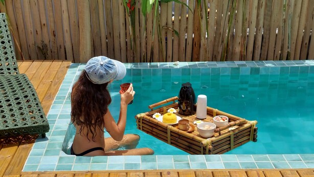 Una persona seduta accanto a una piscina con un vassoio di cibo e bevande.