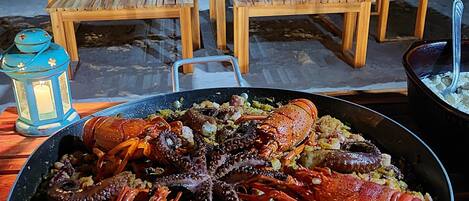 A seafood dish with lobster and octopus, served on a woven mat.