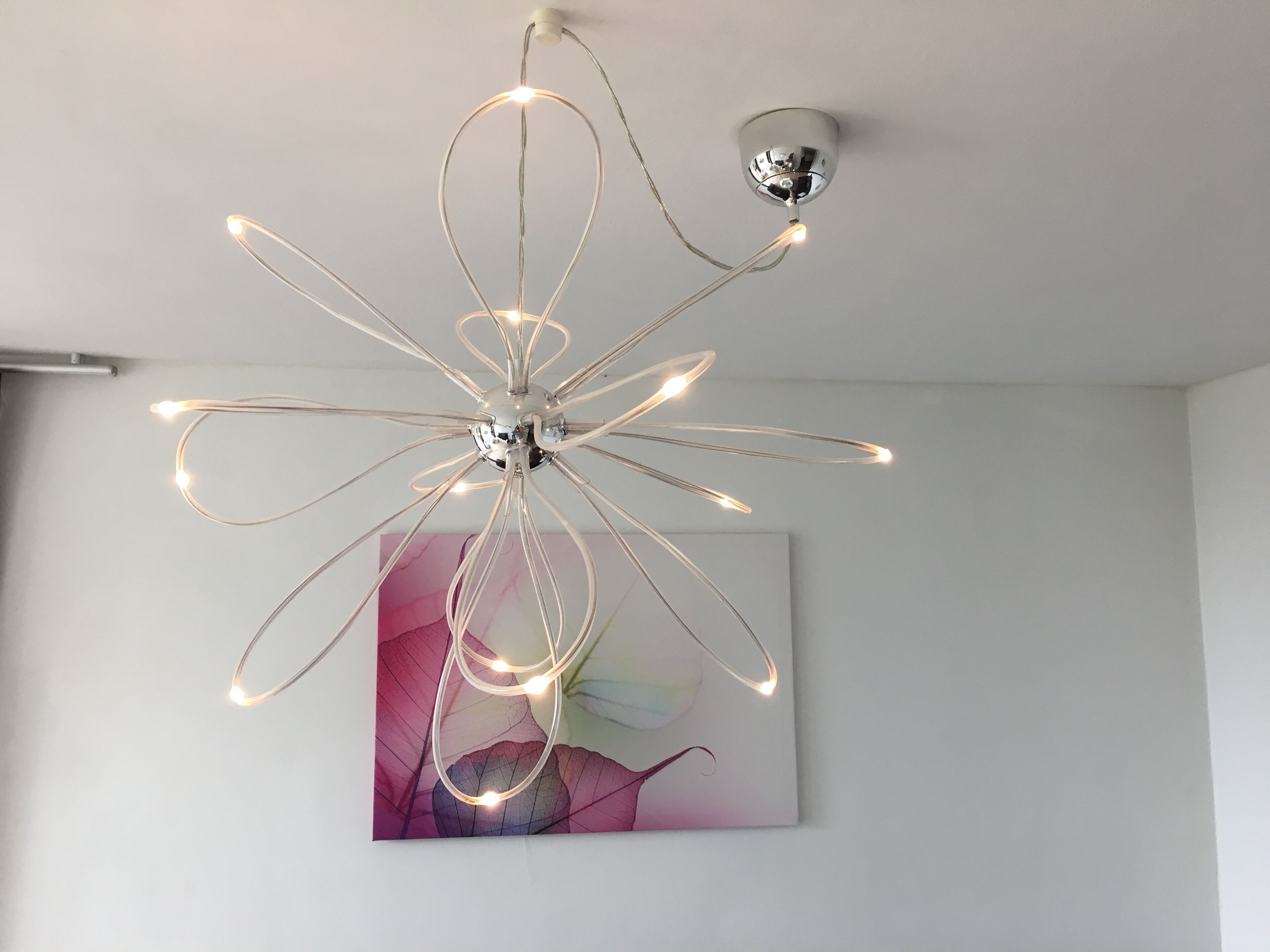 Ein moderner Kronleuchter mit mehreren Leuchten, der an der Decke befestigt ist.
