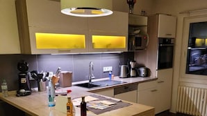 Uma cozinha moderna com ilha central, banquetas, luminária pendente e eletrodomésticos embutidos.