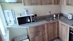 Eine kleine Küche mit Holzausstattung, einer Mikrowelle, einem Spülbecken und einem Wasserkocher.