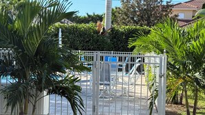 Un área de piscina amurallada con un camino que lleva a una zona de estar junto a la piscina.