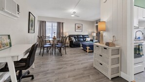 Una sala moderna con comedor, sofá y cocina con pileta y alacenas.