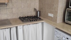 Una cocina compacta con estufa a gas, microondas y lavadora.