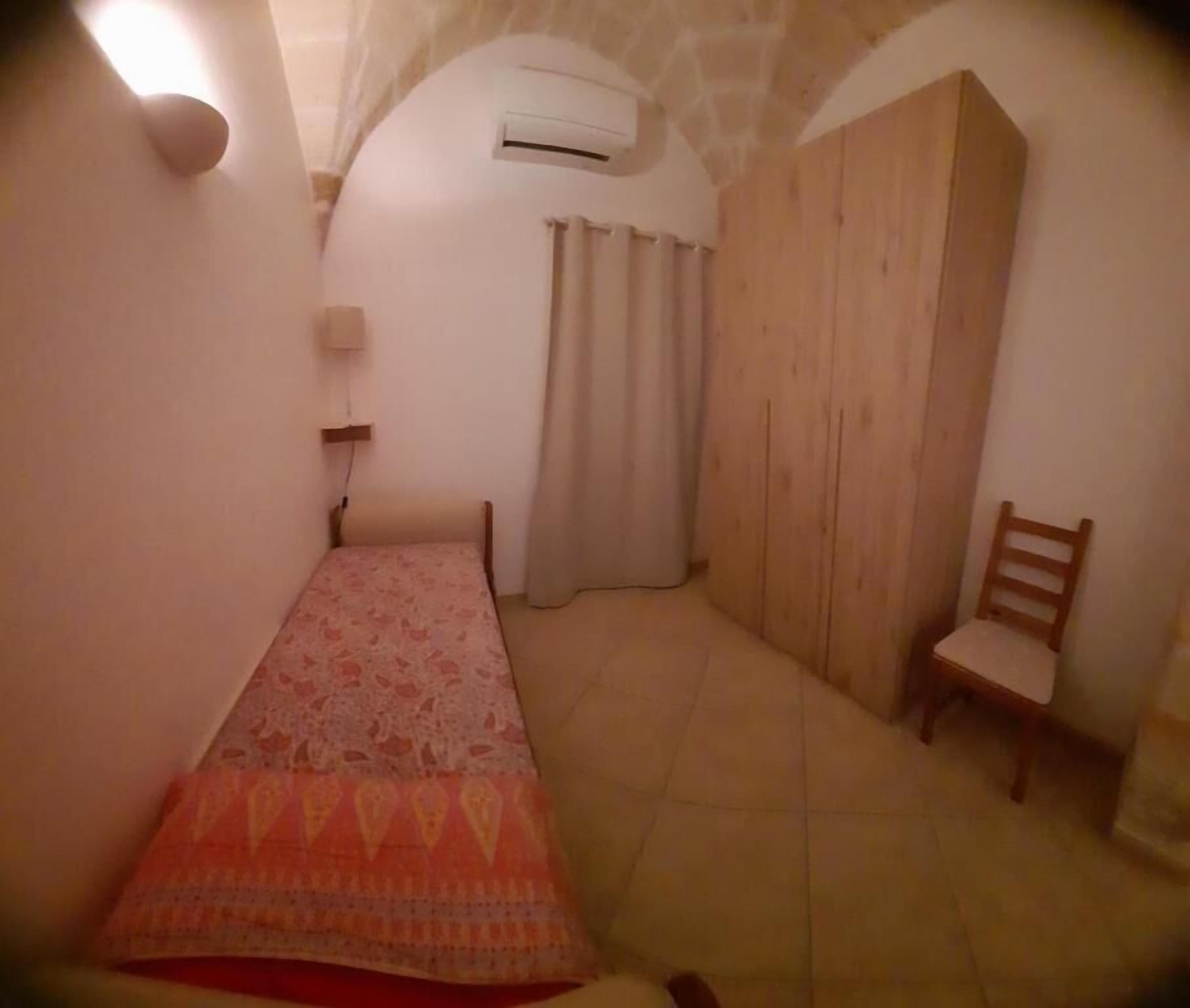 Une petite pièce agréable, dotée d’un lit, d’une chaise, d’une armoire et d’un appareil de climatisation.