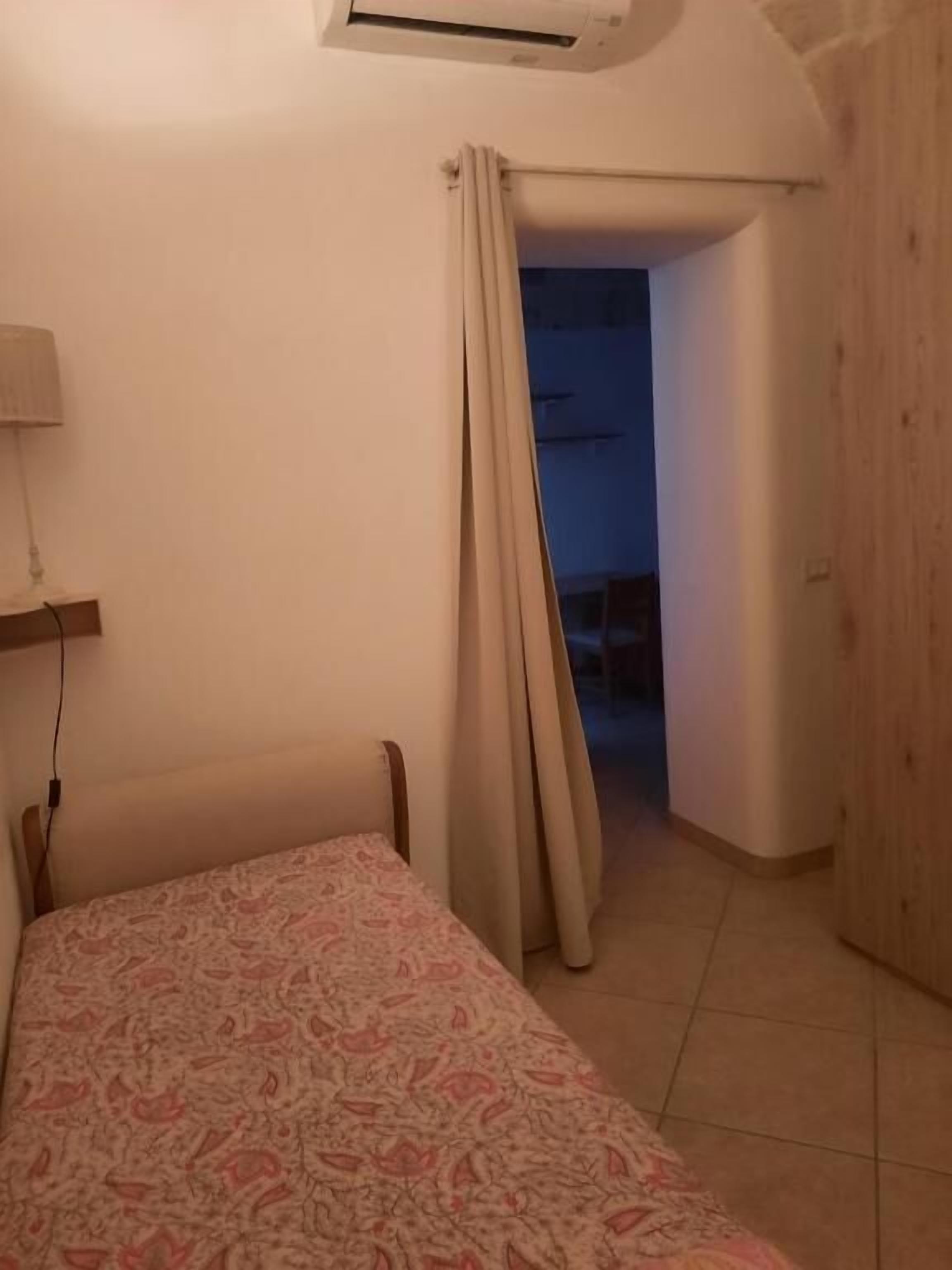 A bedroom with a bed, a lamp, and a wooden door.